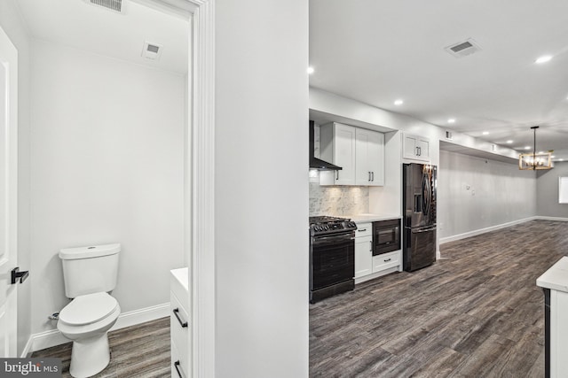 kitchen with backsplash, wall chimney range hood, dark wood finished floors, light countertops, and black appliances