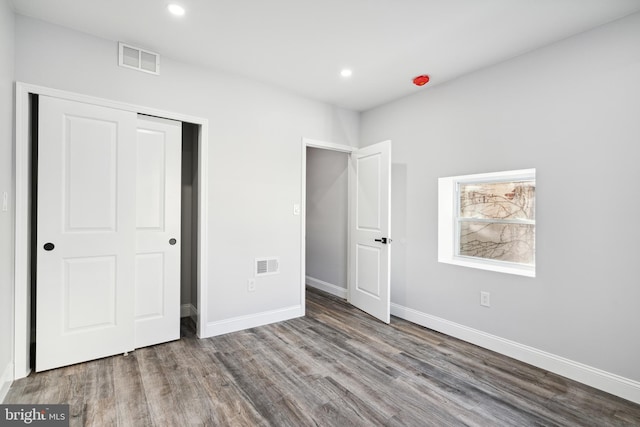 unfurnished bedroom with visible vents, baseboards, a closet, and wood finished floors