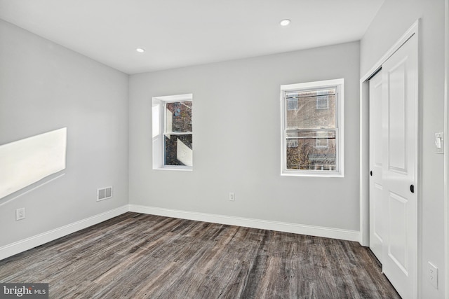 unfurnished bedroom with baseboards, visible vents, recessed lighting, dark wood-type flooring, and a closet