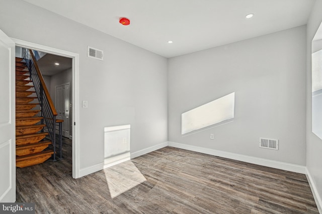 unfurnished room featuring visible vents, stairs, baseboards, and wood finished floors