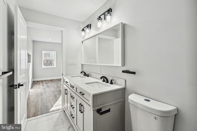 bathroom with double vanity, marble finish floor, toilet, and a sink