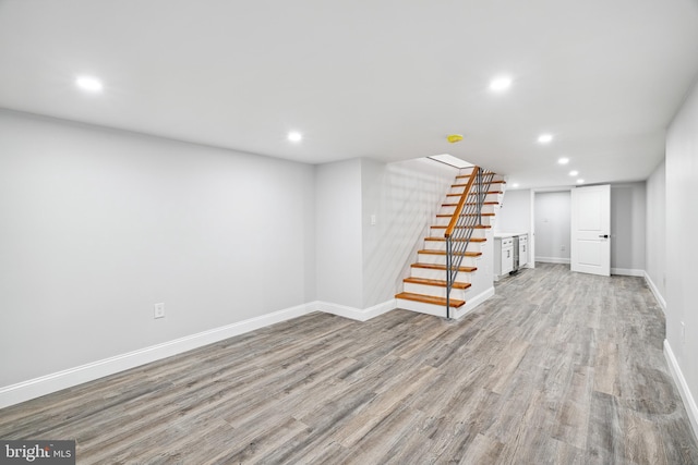 finished below grade area featuring recessed lighting, stairway, baseboards, and light wood-style flooring