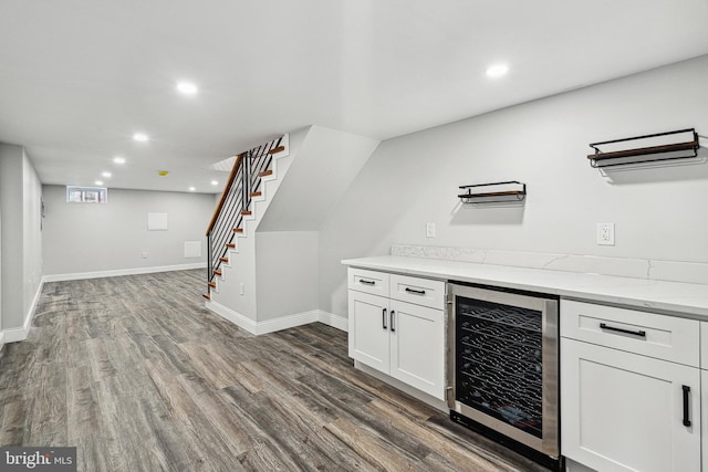 kitchen with white cabinetry, wine cooler, light stone counters, and wood finished floors