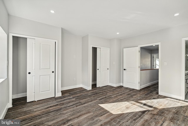 unfurnished bedroom featuring recessed lighting, dark wood-style floors, baseboards, and multiple closets