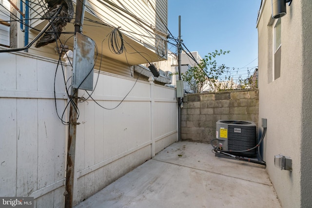 view of side of property featuring a patio, central air condition unit, and fence