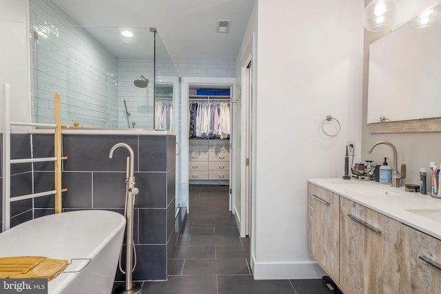 bathroom featuring tile patterned floors, a freestanding tub, a sink, walk in shower, and a spacious closet