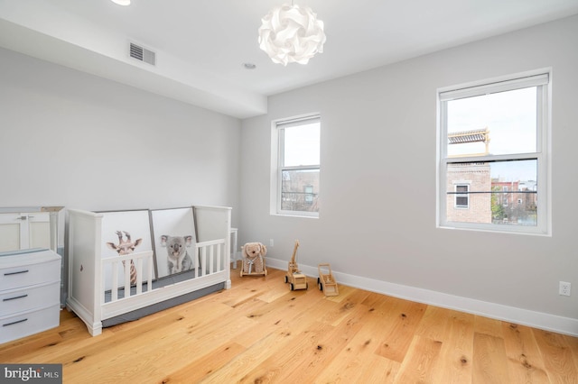 bedroom with visible vents, baseboards, and wood finished floors