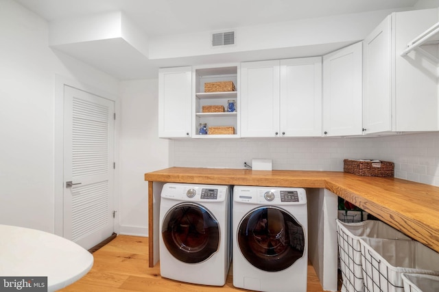 laundry room with visible vents, baseboards, light wood-style floors, cabinet space, and separate washer and dryer