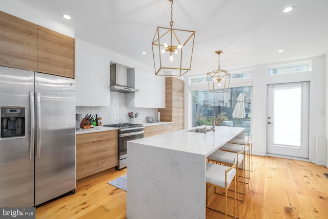 kitchen with a sink, stainless steel appliances, modern cabinets, and wall chimney exhaust hood