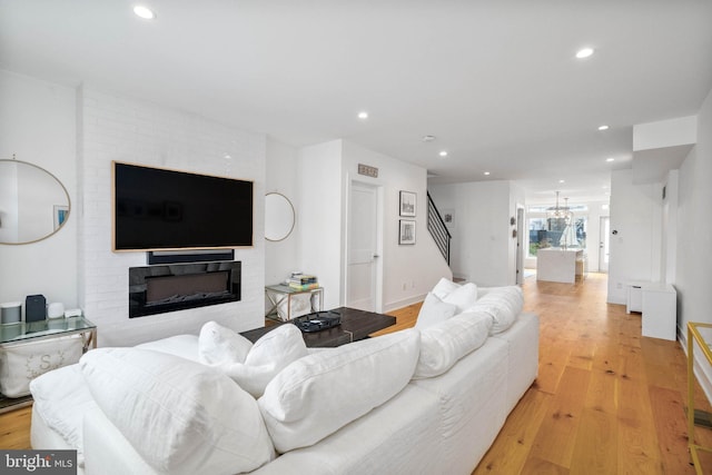 living room with stairs, a notable chandelier, recessed lighting, and light wood-style floors