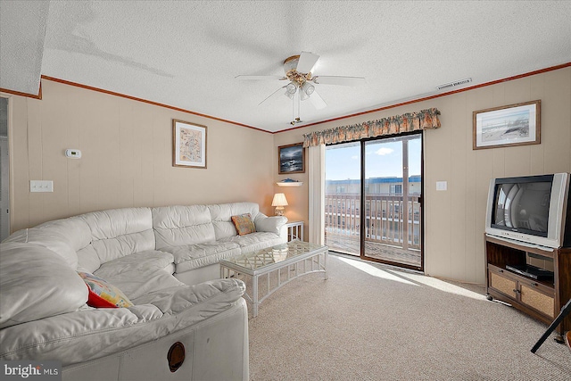 living area featuring visible vents, carpet flooring, crown molding, and a ceiling fan