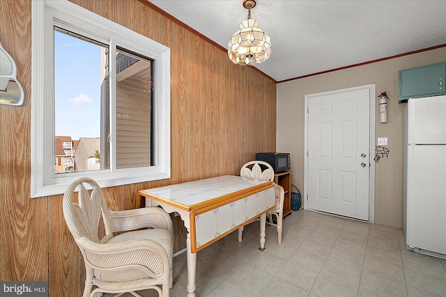 dining room with light tile patterned floors, wooden walls, an inviting chandelier, and crown molding