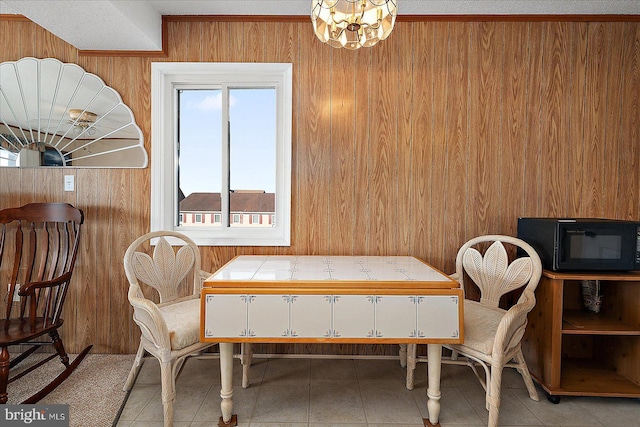 dining space featuring light tile patterned floors, a chandelier, and wood walls