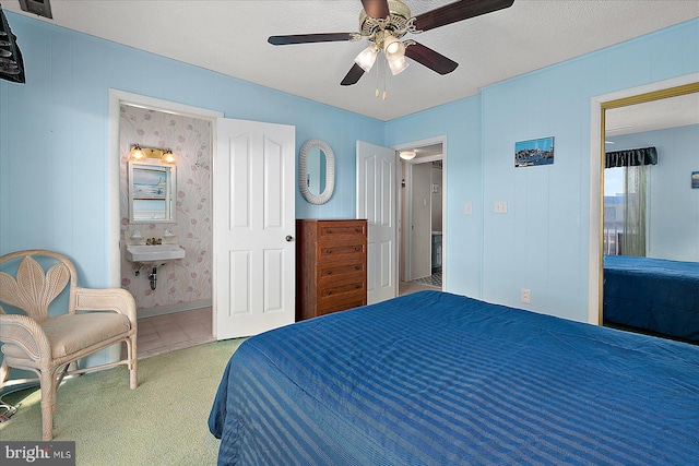 bedroom featuring a sink, a ceiling fan, ensuite bath, and carpet flooring