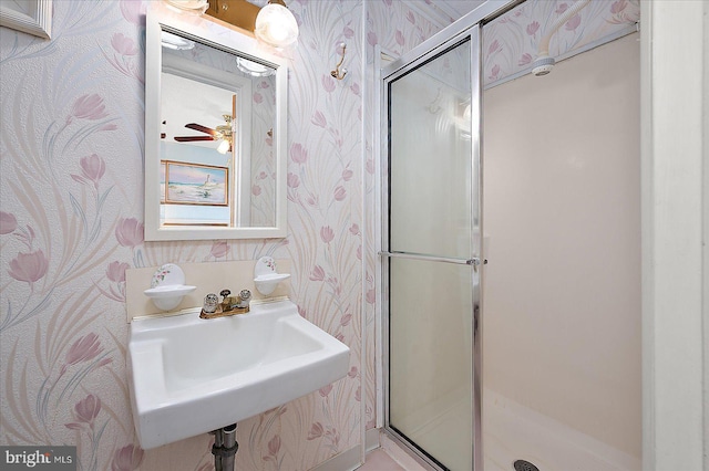 full bathroom featuring a sink, a stall shower, and wallpapered walls