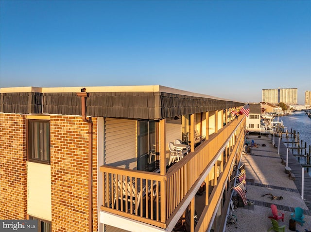 exterior space featuring mansard roof, a water view, and brick siding