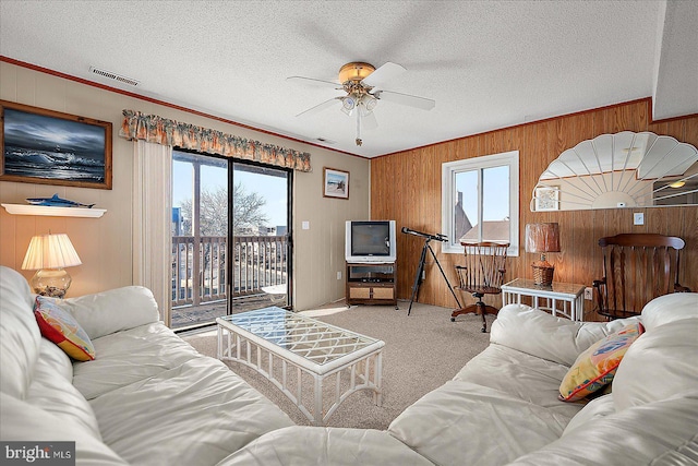 living room with a wealth of natural light, visible vents, carpet floors, and a ceiling fan