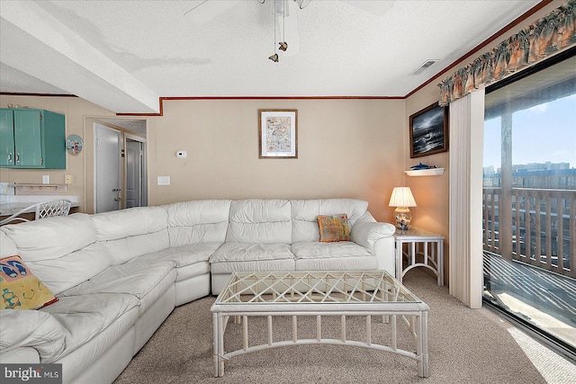 living area featuring visible vents, ceiling fan, ornamental molding, light carpet, and a textured ceiling