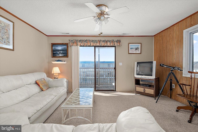 carpeted living room with visible vents, a textured ceiling, crown molding, and a ceiling fan