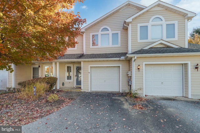 townhome / multi-family property featuring an attached garage, driveway, and roof with shingles