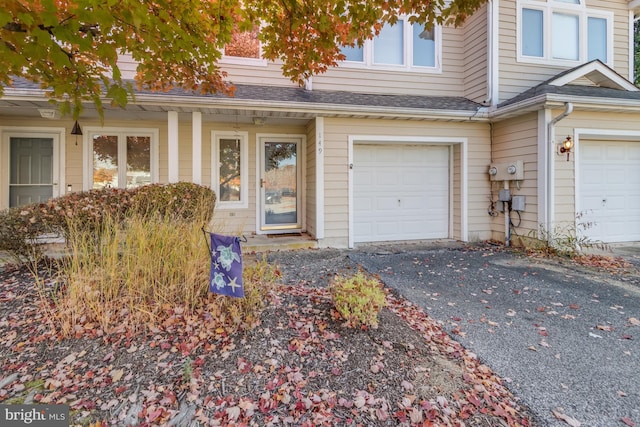 view of front of house featuring an attached garage, driveway, and a shingled roof