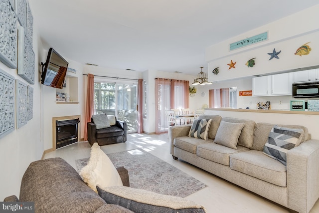 living room with a chandelier and a glass covered fireplace