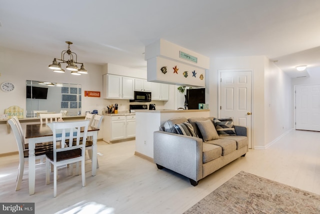 living area featuring an inviting chandelier, baseboards, and light wood-style floors