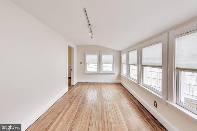 unfurnished sunroom with rail lighting and lofted ceiling