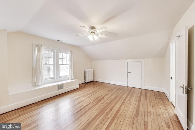 bonus room with visible vents, light wood-style flooring, radiator heating unit, and baseboards