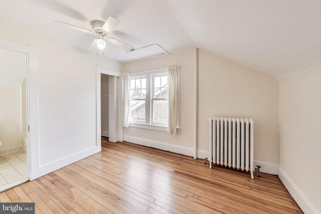 unfurnished bedroom with radiator, baseboards, and light wood-style floors