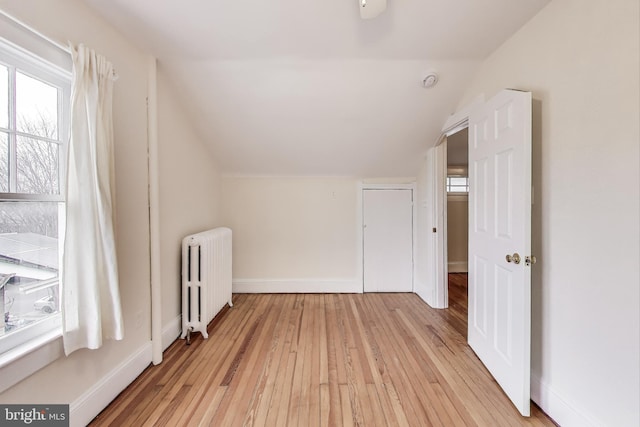 bonus room with radiator, baseboards, light wood-style floors, and vaulted ceiling