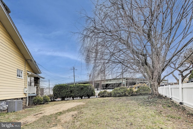 view of yard with central air condition unit and fence