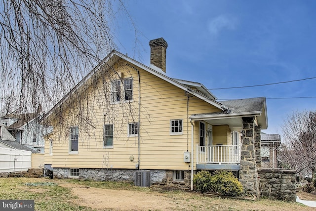 view of home's exterior with central AC unit and a chimney