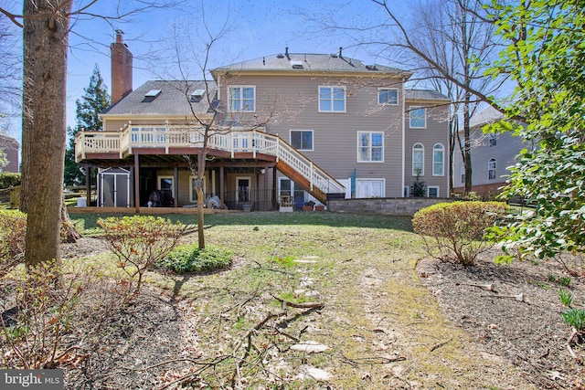 rear view of house featuring stairway, a yard, a deck, and a chimney