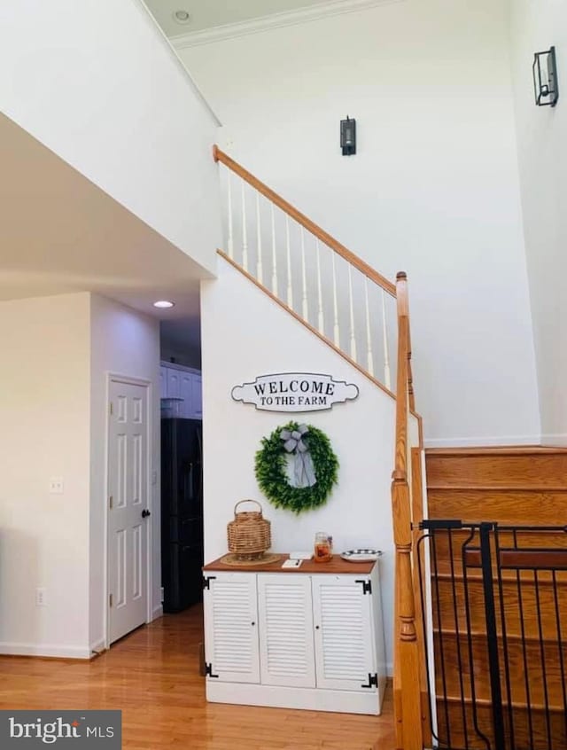 stairway with baseboards, a high ceiling, and wood finished floors