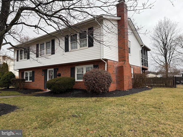 view of front of home with a front lawn, fence, and brick siding