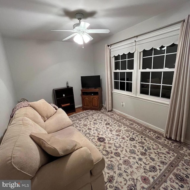 living area with baseboards and a ceiling fan