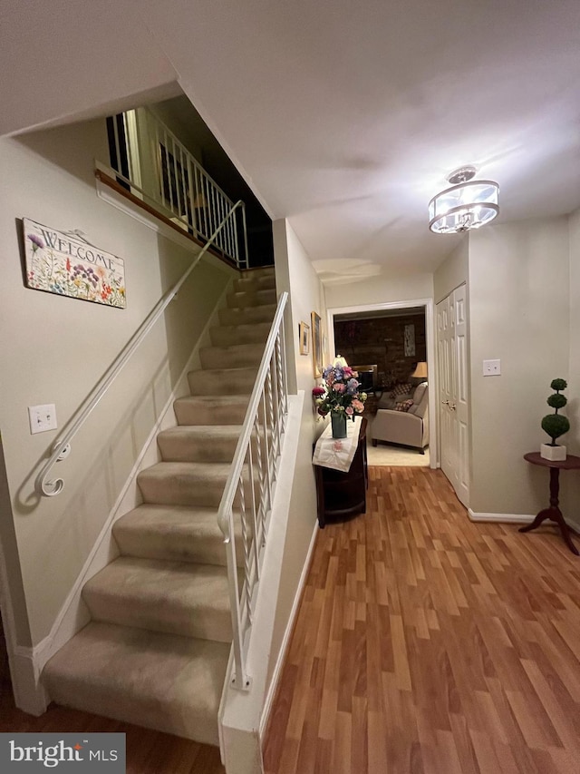 staircase with a glass covered fireplace, baseboards, and wood finished floors