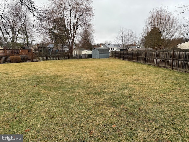 view of yard with an outdoor structure, a fenced backyard, and a shed