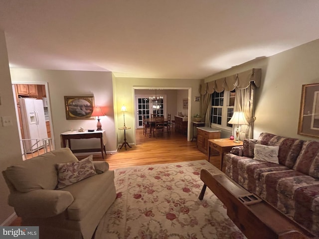 living area with a chandelier, light wood-style flooring, and baseboards