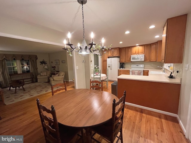 dining room with recessed lighting, baseboards, an inviting chandelier, and light wood-style flooring