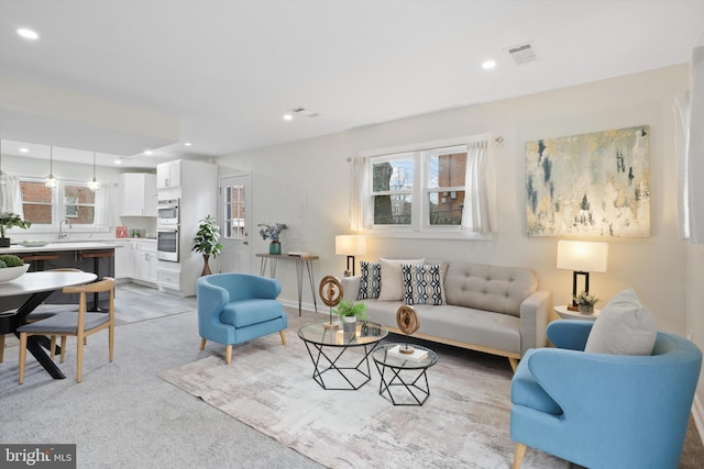 living area with light carpet, visible vents, and recessed lighting