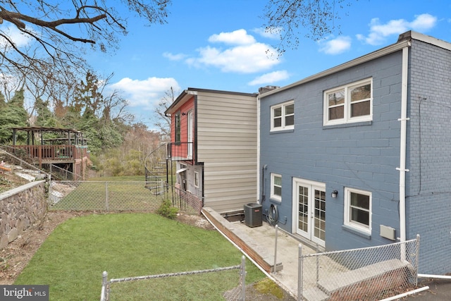 view of home's exterior with central AC, a lawn, french doors, and fence private yard