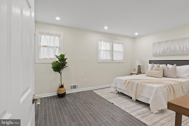 bedroom featuring dark wood-type flooring, multiple windows, baseboards, and visible vents