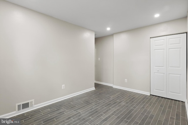 empty room featuring recessed lighting, visible vents, baseboards, and dark wood-type flooring