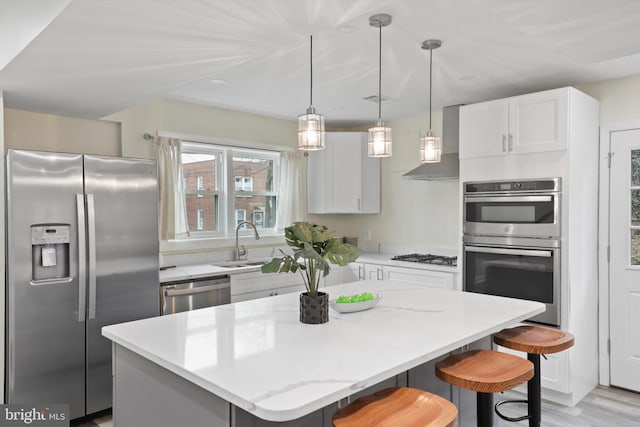 kitchen featuring a kitchen bar, a sink, a kitchen island, appliances with stainless steel finishes, and white cabinets