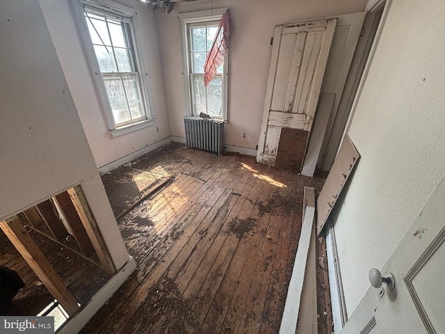 unfurnished bedroom with radiator, baseboards, and wood-type flooring