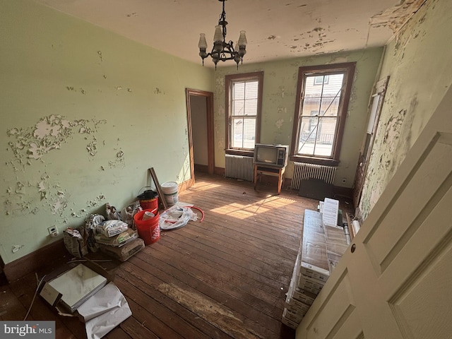 interior space with hardwood / wood-style floors, a notable chandelier, radiator heating unit, and baseboards