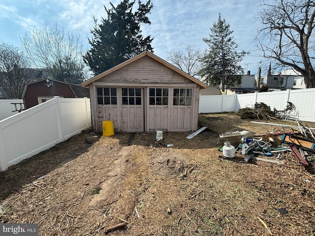 rear view of house with an outdoor structure and a fenced backyard