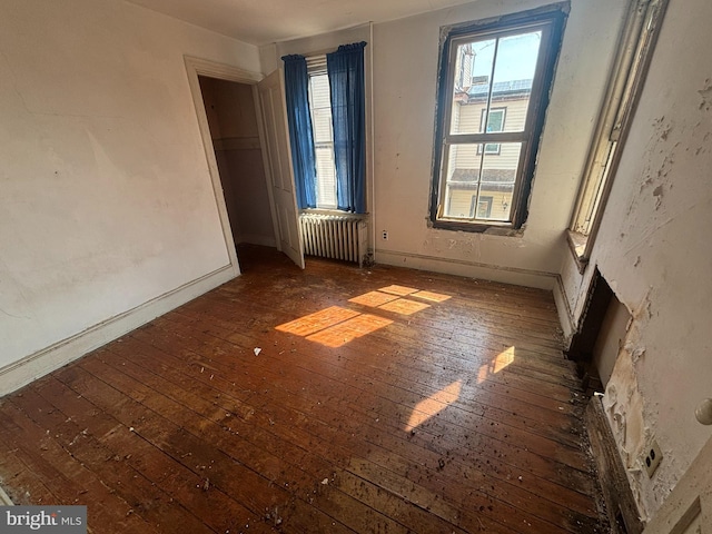 unfurnished room featuring radiator, plenty of natural light, and wood-type flooring